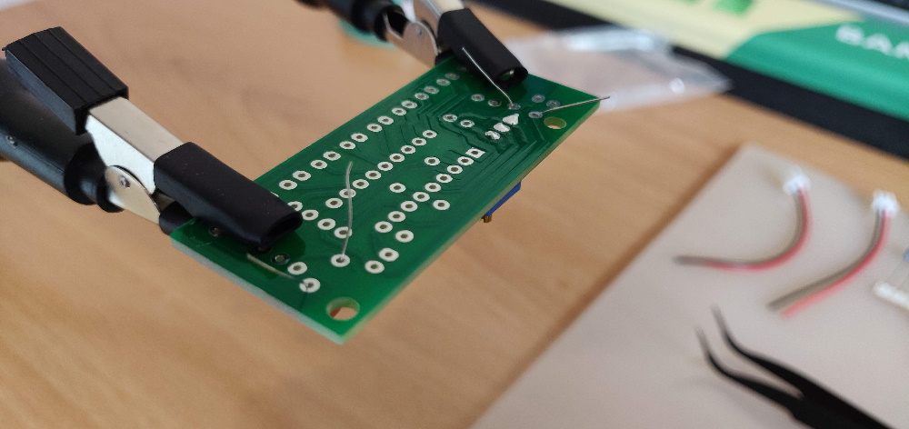 De helping hands helpen ook vandaag weer mee met het vasthouden van het PCB. Ik begin met de keramische condensatoren. Er zitten lange poten aan die ik buig zodat ze blijven hangen aan het PCB.